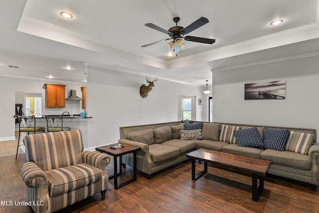 living room featuring ceiling fan, ornamental molding, a tray ceiling, and dark hardwood / wood-style floors