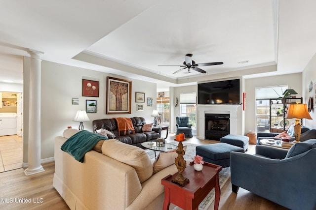 living room with ceiling fan, a raised ceiling, washer / dryer, and light hardwood / wood-style flooring