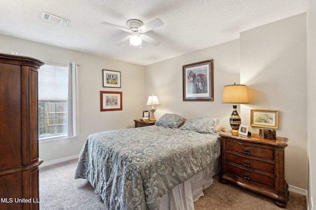 bedroom with a textured ceiling, light colored carpet, and ceiling fan