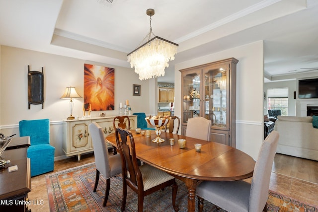 dining space with a tray ceiling, crown molding, and an inviting chandelier