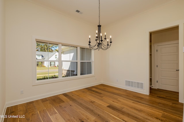 unfurnished dining area with wood-type flooring and a chandelier