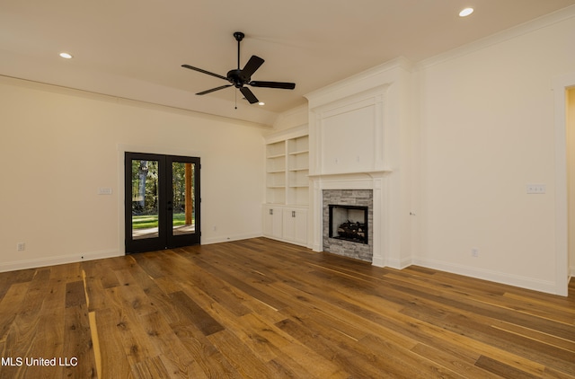 unfurnished living room featuring dark hardwood / wood-style flooring, a stone fireplace, and ornamental molding