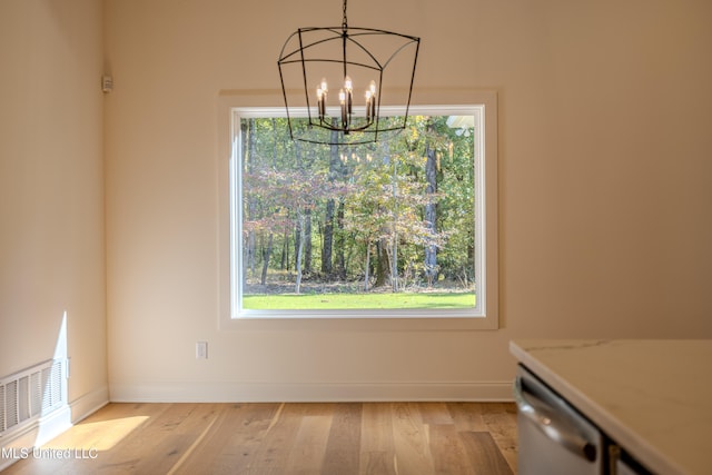 unfurnished dining area with light hardwood / wood-style flooring and a notable chandelier