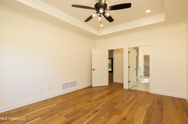 unfurnished room with ceiling fan, a raised ceiling, and light wood-type flooring