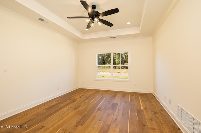 empty room featuring hardwood / wood-style floors, a raised ceiling, and ceiling fan