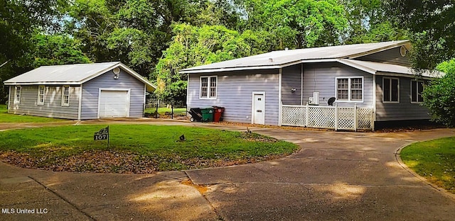 exterior space featuring a front yard, a garage, and an outbuilding