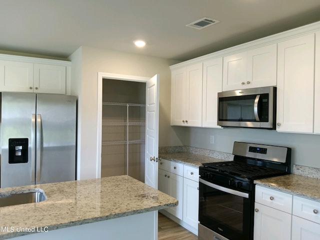 kitchen featuring light stone countertops, white cabinetry, and stainless steel appliances