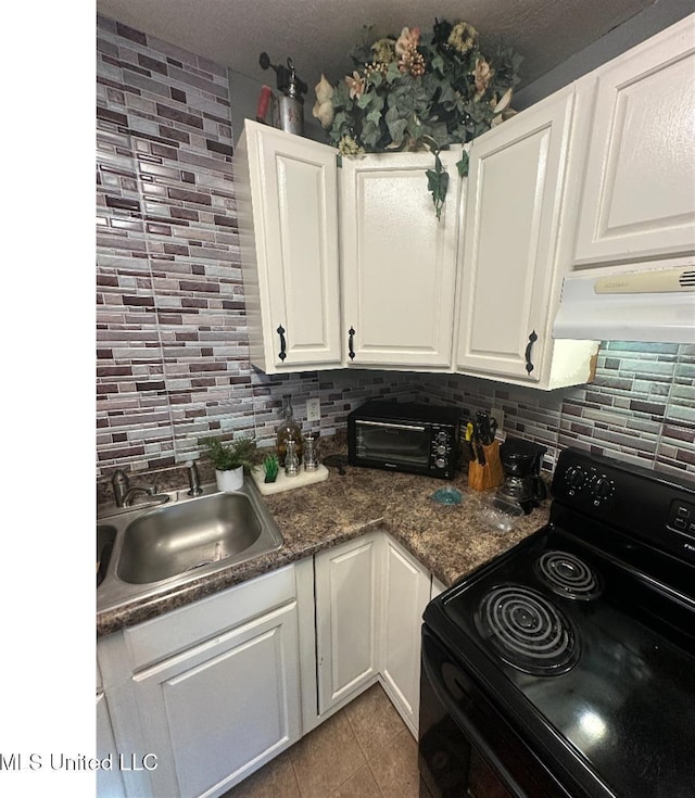 kitchen with tasteful backsplash, electric range, white cabinets, and a sink