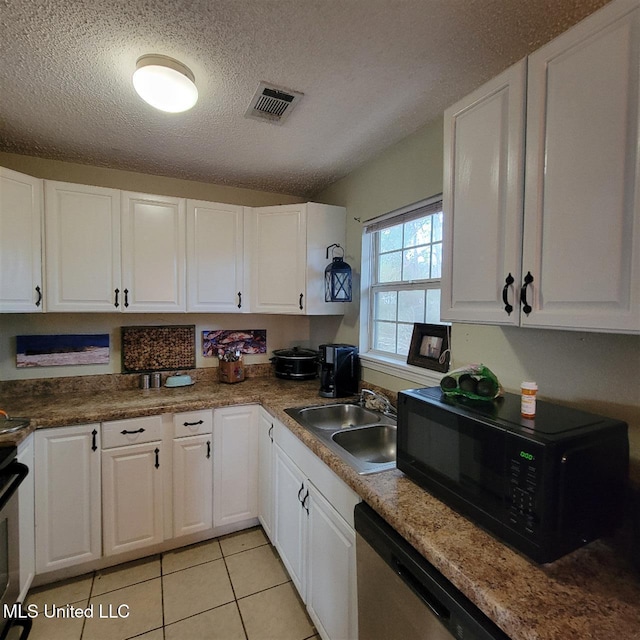 kitchen with visible vents, a sink, white cabinetry, black microwave, and light tile patterned floors