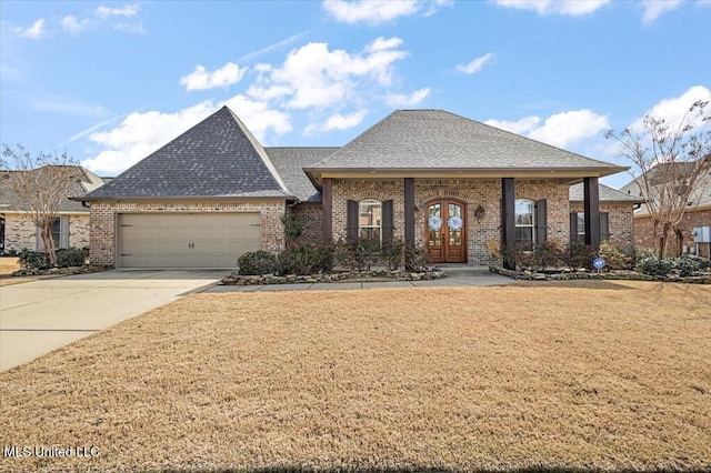 view of front facade featuring brick siding, a shingled roof, a front yard, french doors, and driveway