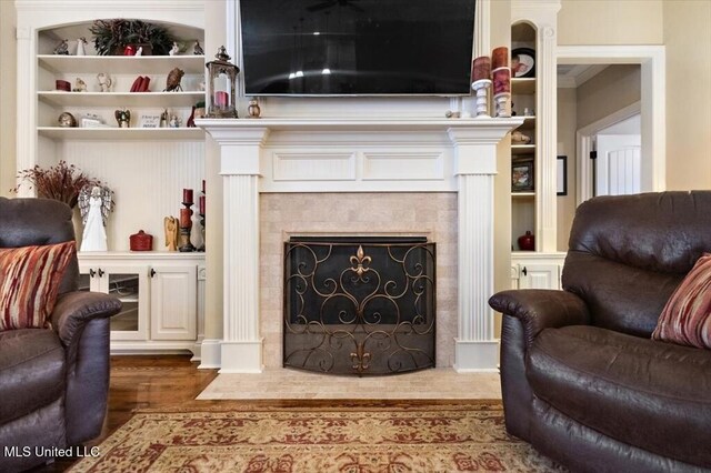 living room featuring a fireplace, built in shelves, and wood finished floors