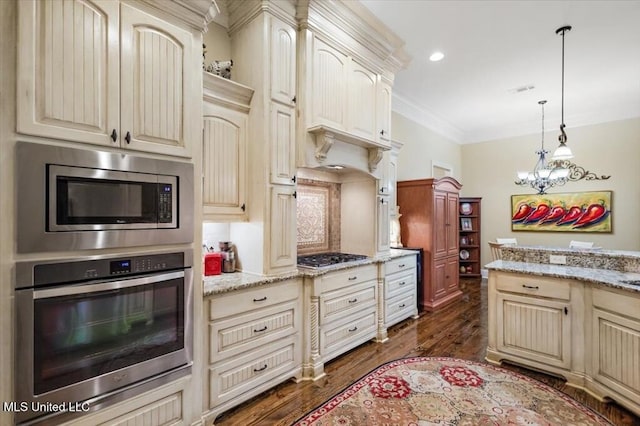 kitchen featuring stainless steel appliances, cream cabinetry, ornamental molding, and dark wood finished floors