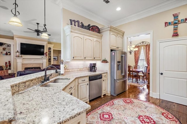 kitchen featuring a sink, ornamental molding, stainless steel appliances, cream cabinets, and open floor plan