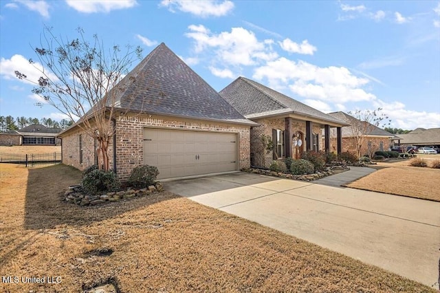 french provincial home featuring brick siding, driveway, roof with shingles, and fence