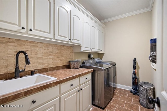 laundry room with baseboards, cabinet space, ornamental molding, a sink, and washer and clothes dryer