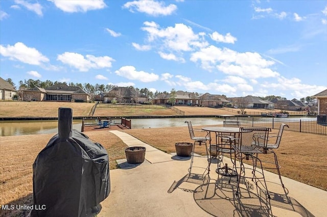 view of patio / terrace featuring area for grilling, fence, a residential view, and a water view