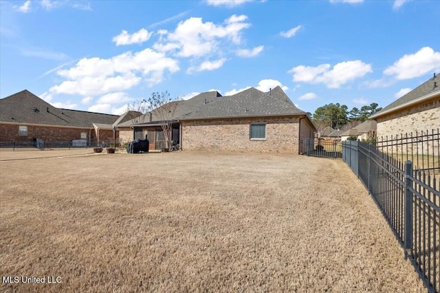 rear view of property featuring fence and brick siding