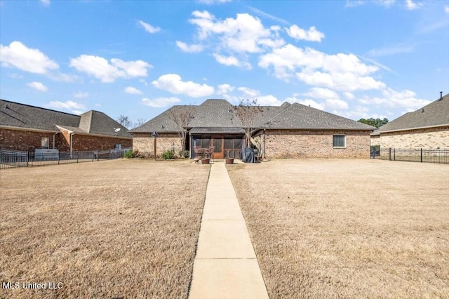 view of front facade with brick siding, a fenced backyard, and a front yard