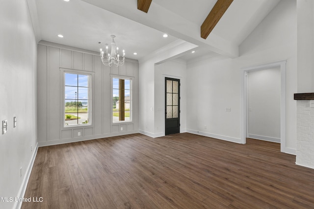 empty room featuring lofted ceiling with beams, dark hardwood / wood-style flooring, a brick fireplace, and an inviting chandelier