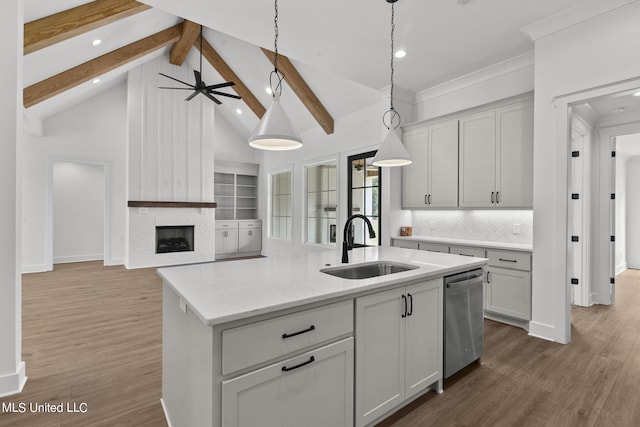 kitchen with dishwasher, dark hardwood / wood-style flooring, beamed ceiling, pendant lighting, and a center island with sink