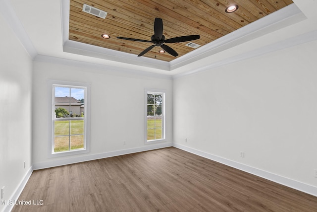 unfurnished room with crown molding, a healthy amount of sunlight, hardwood / wood-style flooring, and a tray ceiling