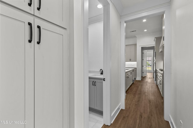 hall with sink, crown molding, and hardwood / wood-style flooring