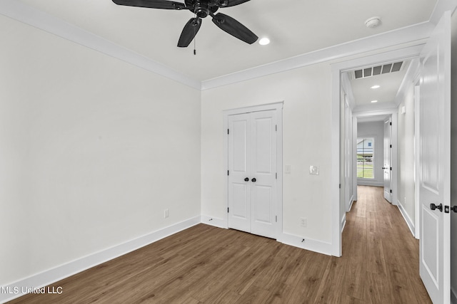 unfurnished bedroom with a closet, ceiling fan, crown molding, and hardwood / wood-style floors