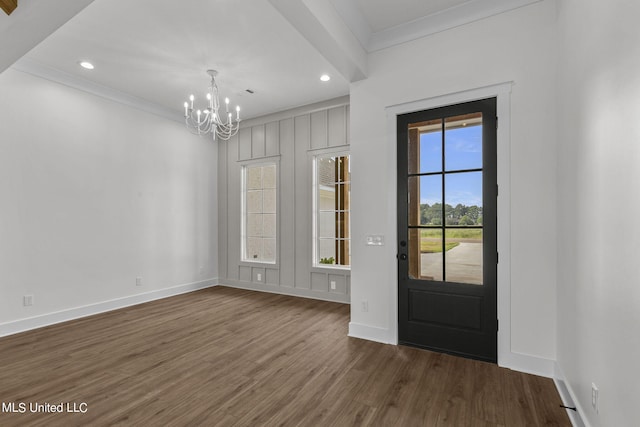 entrance foyer featuring ornamental molding, dark hardwood / wood-style flooring, and an inviting chandelier