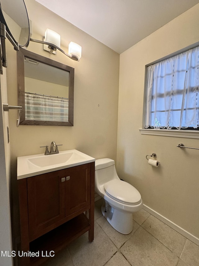 bathroom featuring toilet, tile patterned floors, baseboards, and vanity