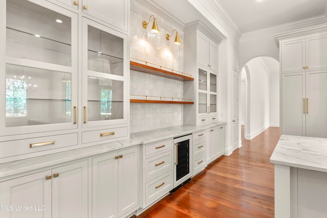 kitchen with white cabinetry, wine cooler, dark wood-type flooring, and ornamental molding