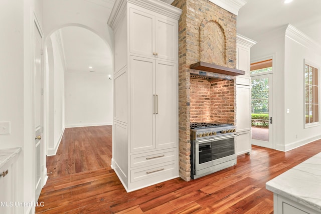 kitchen featuring high end range, ornamental molding, light hardwood / wood-style flooring, and white cabinets