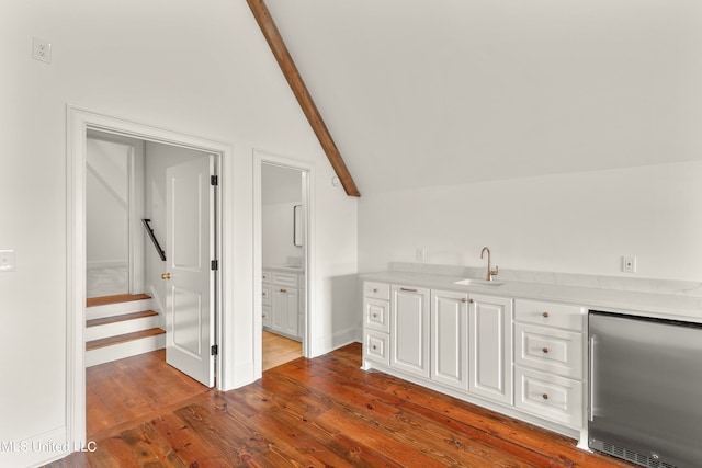 interior space featuring dark hardwood / wood-style floors, sink, stainless steel fridge, lofted ceiling with beams, and white cabinetry