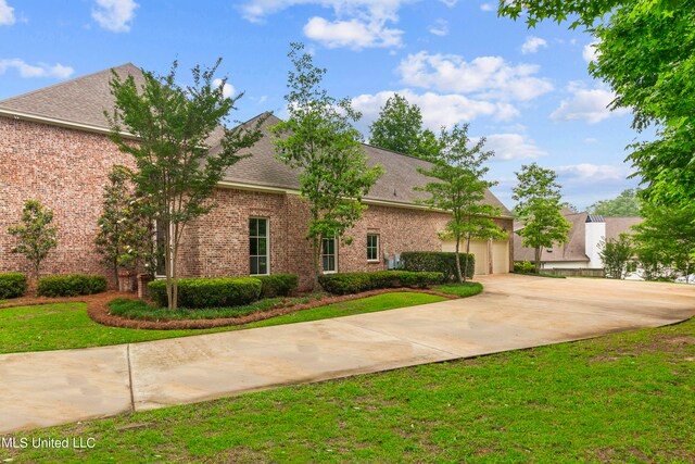 view of front of house with brick siding, a front yard, roof with shingles, a garage, and driveway