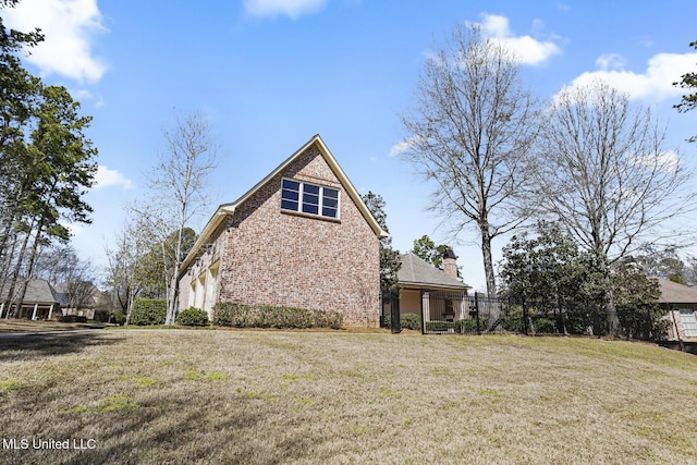 view of home's exterior featuring a lawn, brick siding, and fence