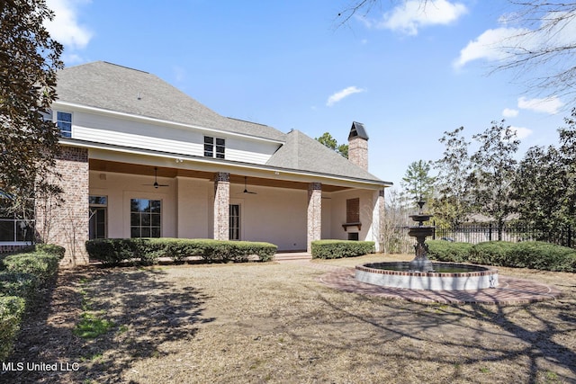 exterior space with a ceiling fan, a chimney, and fence