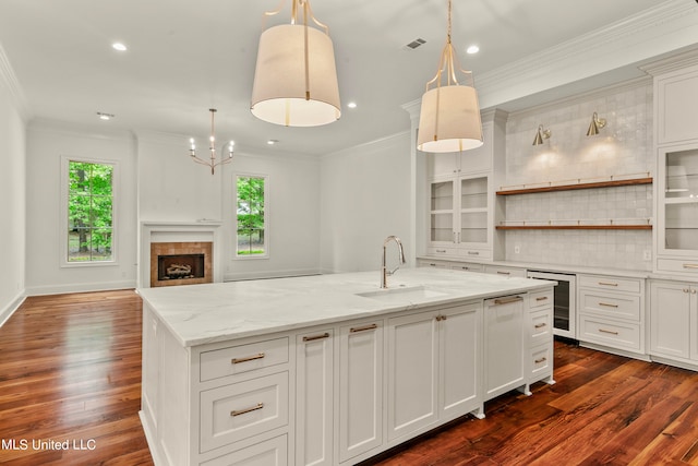 kitchen featuring dark wood-type flooring, hanging light fixtures, backsplash, a large island, and a fireplace