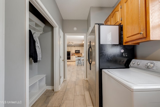 laundry room featuring wood tiled floor, washer / clothes dryer, and cabinet space