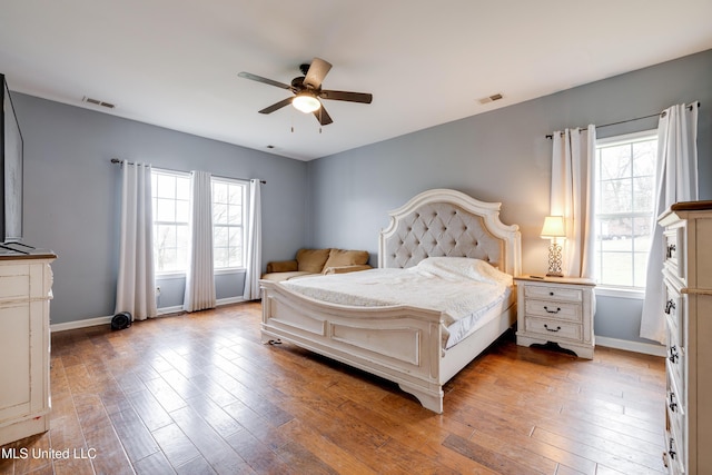 bedroom featuring light wood-style floors, visible vents, and baseboards