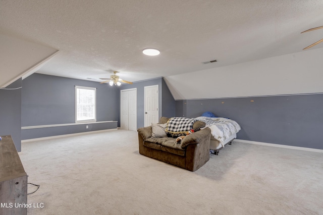 bedroom with lofted ceiling, light colored carpet, visible vents, and a textured ceiling