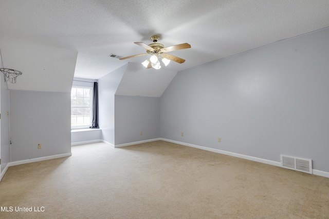 additional living space featuring a textured ceiling, visible vents, and light colored carpet