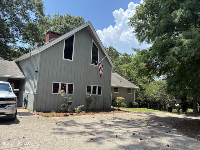 6825 Shore Dr, Ocean Springs, MS 39564 - view of property exterior featuring a chimney, board and batten siding, and driveway
