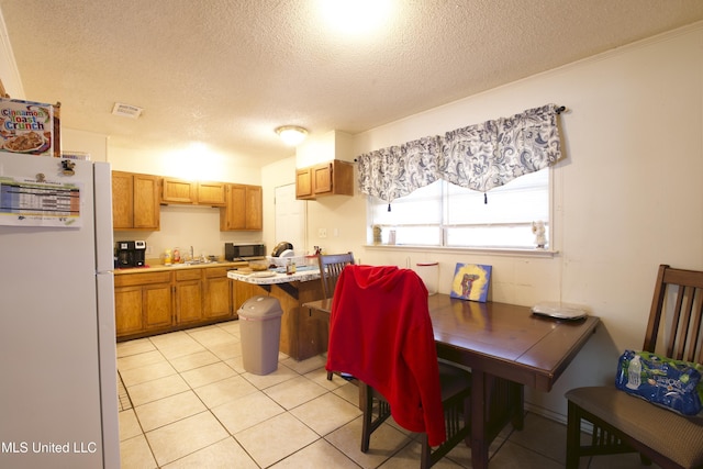 kitchen featuring sink, a textured ceiling, light tile patterned floors, and white refrigerator