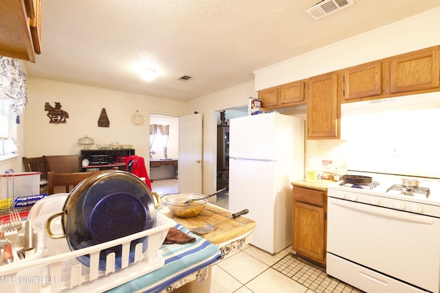 kitchen with light tile patterned floors, white appliances, and a textured ceiling