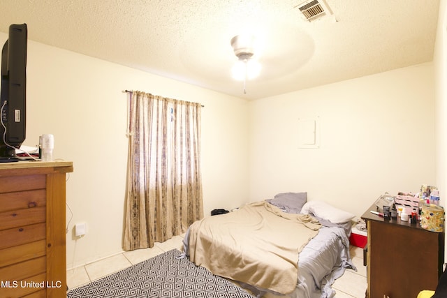 tiled bedroom with ceiling fan and a textured ceiling