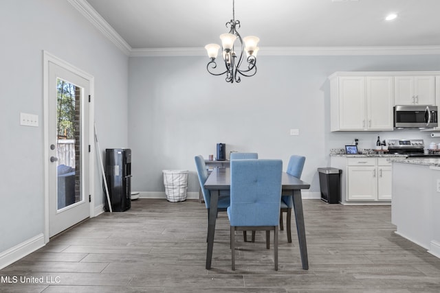 dining area with crown molding, a notable chandelier, and wood finished floors