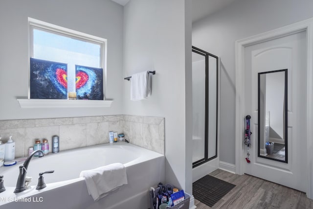 bathroom with a shower stall, a bath, and wood finished floors