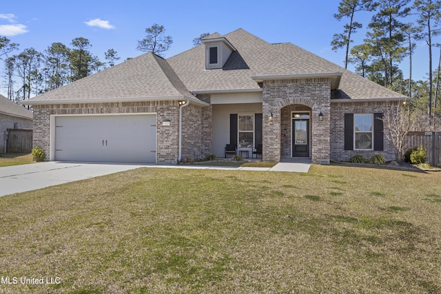 french country home with fence, roof with shingles, an attached garage, a front yard, and brick siding