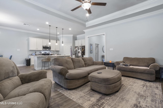 living area with visible vents, crown molding, baseboards, and wood finished floors