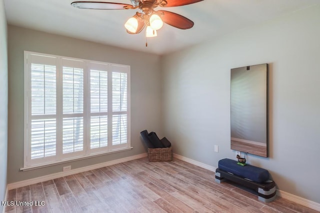 empty room featuring wood finished floors, a ceiling fan, plenty of natural light, and baseboards