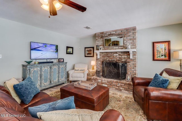 living area with a ceiling fan, a brick fireplace, and wood finished floors